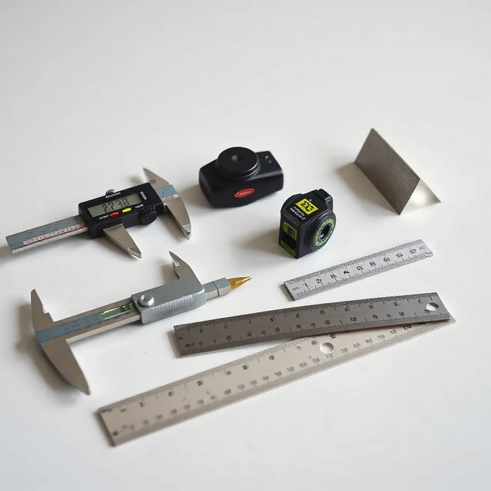 Digital caliper, micrometer, laser level, and tape measure arranged on a workbench for accurate measurements