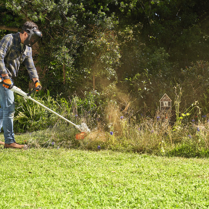 STIHL FSA 57 cordless grass trimmer in use along a garden border, operator wearing face protection
