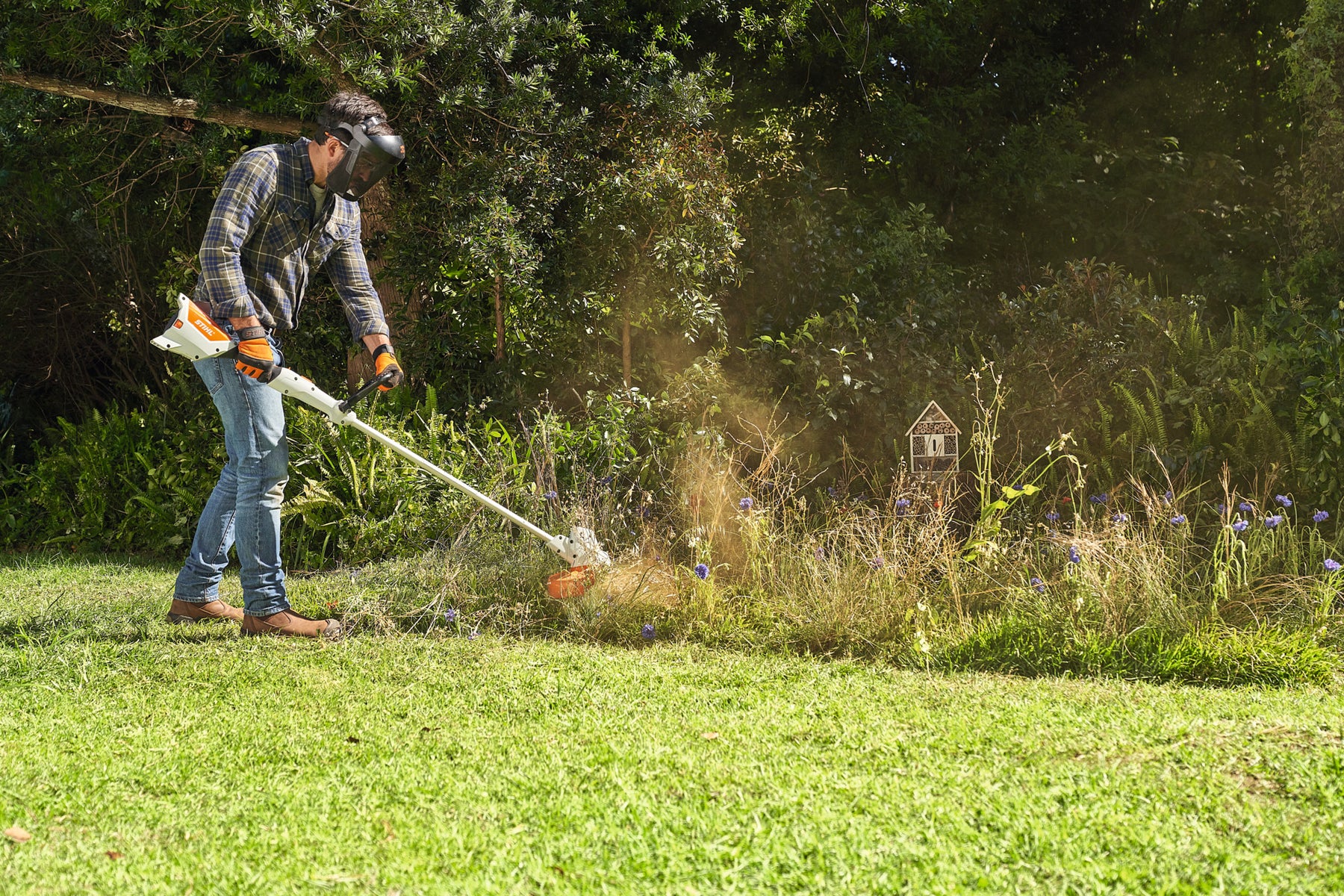 STIHL FSA 57 cordless grass trimmer in use along a garden border with face protection